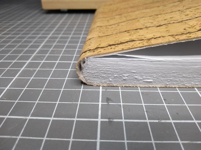 A closeup of the bottom end of the spine. There's a small gap between cover and text block, and the signatures aren't quite straight.