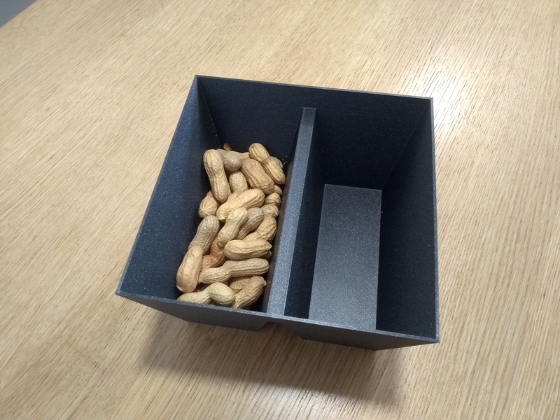 A 3D-printed bowl with two halves, one empty, the other filled with peanuts.